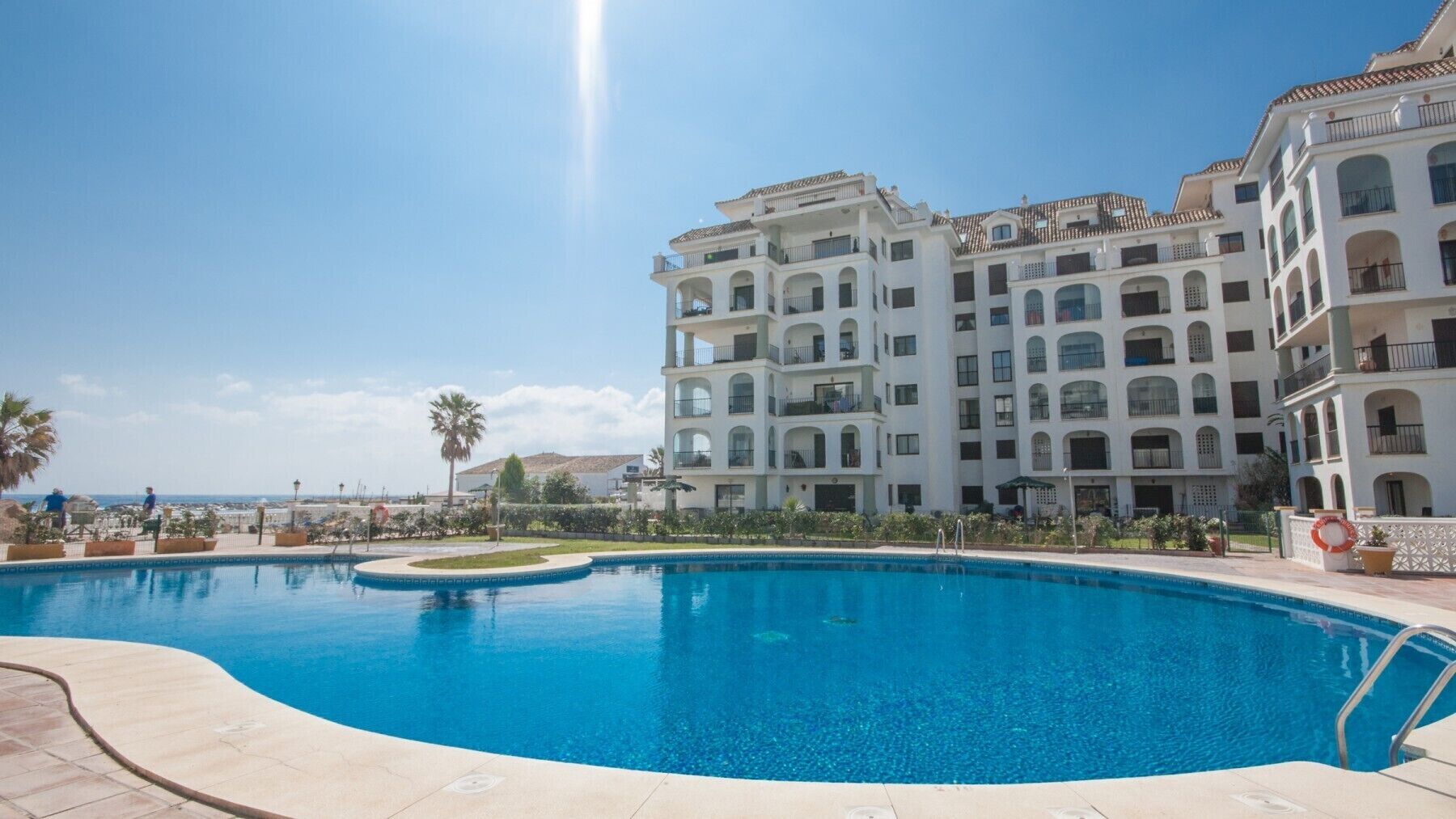 A swimming pool with a clear view of a multi-story hotel building in the background.