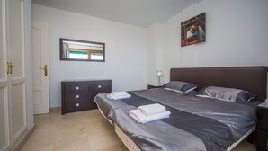 Un dormitorio con cama, cómoda, ventana y un cuadro en la pared.