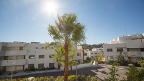 Ett modernt bostadsområde med vita byggnader, en central palmpalm och en klar himmel.