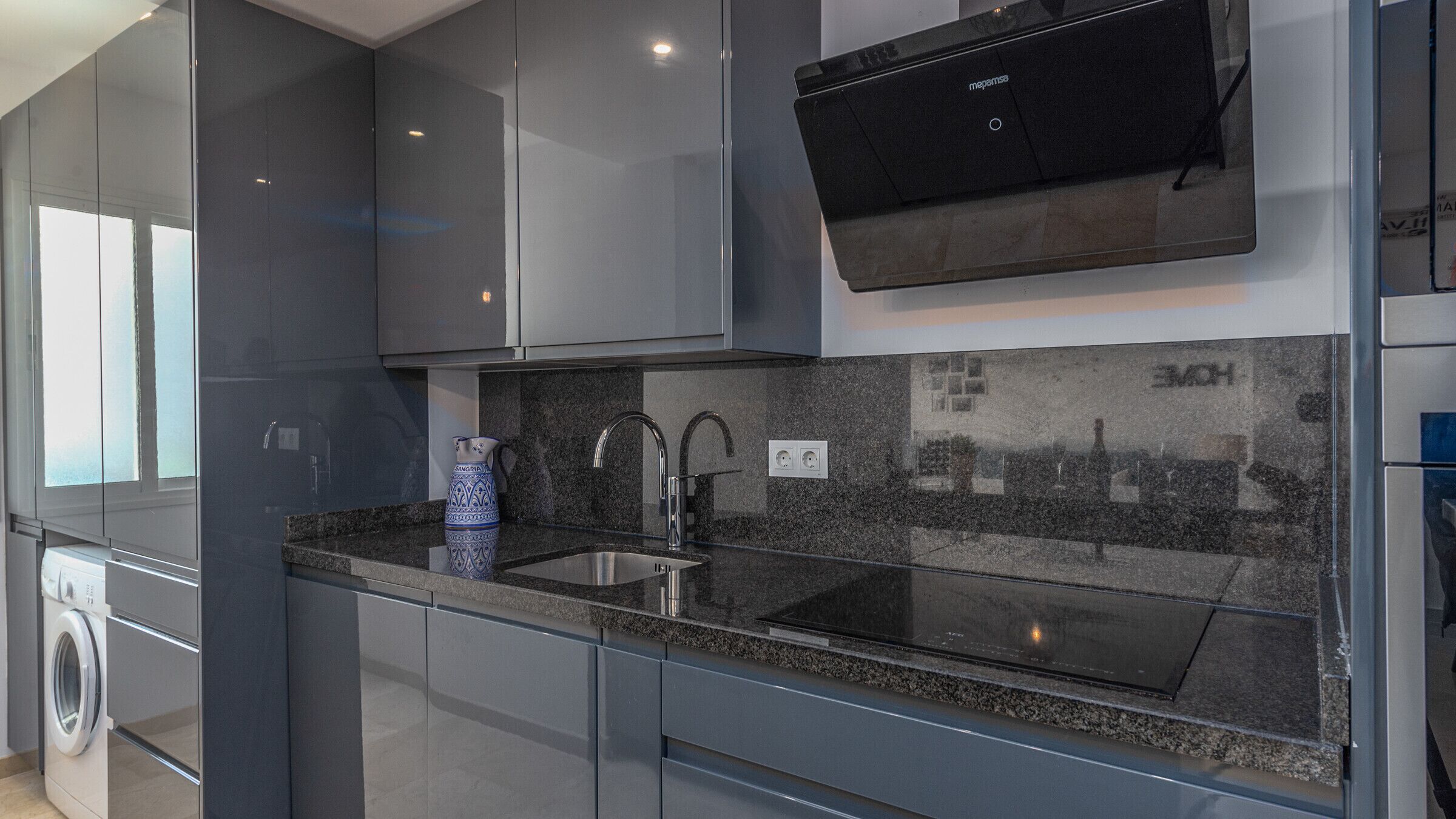 Una cucina moderna con lavello in acciaio inossidabile, forno a incasso e lavastoviglie.