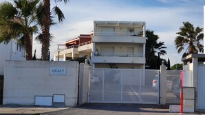 A gated residential area with a multi-story building, palm trees, and a clear sky. - Sunny apartment overlooking Etang de Thau (5 km from the sea) (marseillan)