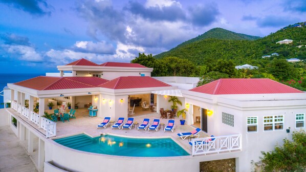 Relax by the resort's spacious pool, surrounded by lush greenery and a distant mountain view.