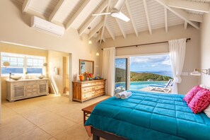 Relax in this serene bedroom with a large bed, dresser, and vanity, offering a scenic view.