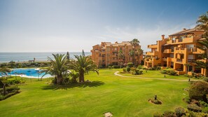 Un complexe hôtelier doté d’une piscine, d’une pelouse bien entretenue et offrant une vue sur la plage.