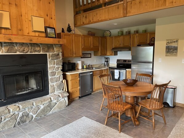 A kitchen with wooden cabinets, a stone fireplace, a dining table with chairs, and stainless steel appliances. - 1 bedroom accommodation in Davis (Davis)