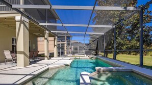 A swimming pool with a covered area, lounge chairs, and a view of buildings in the background.