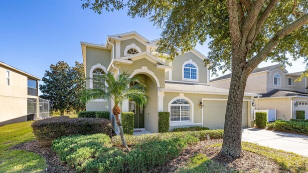 A residential house with a front yard, a palm tree, and a driveway.