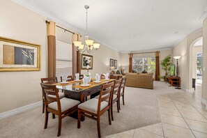 A dining area with a table set for six, surrounded by wooden chairs. - 537 Large 4BR Pool/Spa Conservation Views.2 Masters.Near Disney (Davenport)