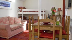 Una habitación acogedora con literas, un sofá, una mesa de comedor con sillas, un televisor y una ventana con vistas al exterior.