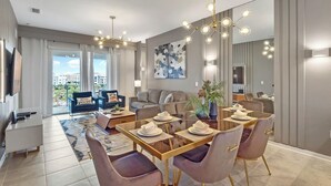 A modern living room with a dining area, large windows, and a city view.