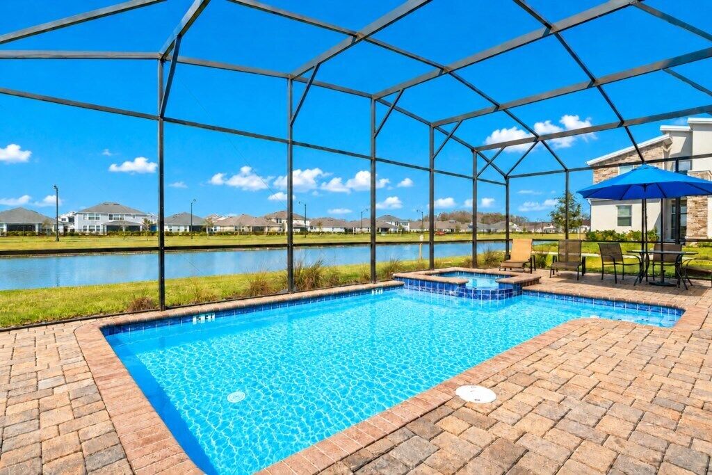 A swimming pool with a clear view of a lake and houses in the background.