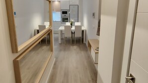 A modern interior with a wooden-framed mirror, a dining area with a white table and chairs, and a kitchen in the background. - NON STRESS: Charming apartment (València)