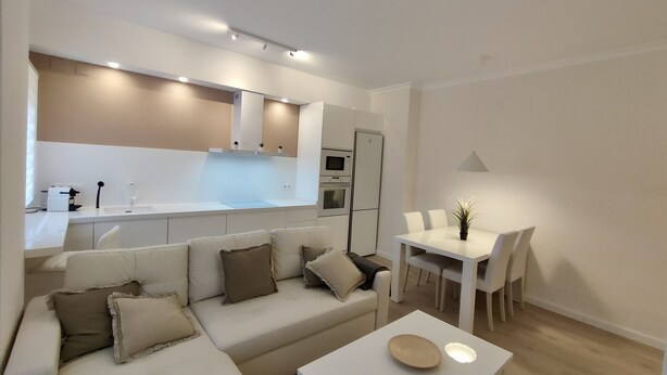 A modern living space with a sofa, a dining table, and a kitchen area. - NON STRESS: Charming apartment (València)