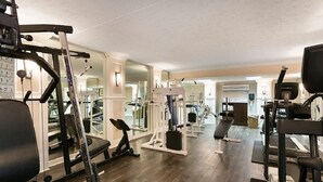 Une salle de sport équipée de divers appareils d’entraînement, notamment des tapis de course, des appareils de musculation et des poids libres.