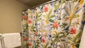 A bathroom with a toilet, a shower curtain with a floral pattern, and a towel hanging on the wall. - Cute Studio!  Remodeled!  Direct Ocean Front! Pirates Cove 6th Floor (Daytona Beach)
