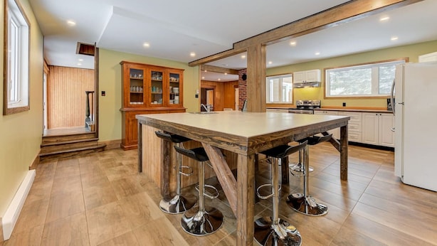 A spacious kitchen with a large island, wooden cabinets, and a modern design. - 2355/2 · Villa des pins (Saint-Gabriel-de-Valcartier)