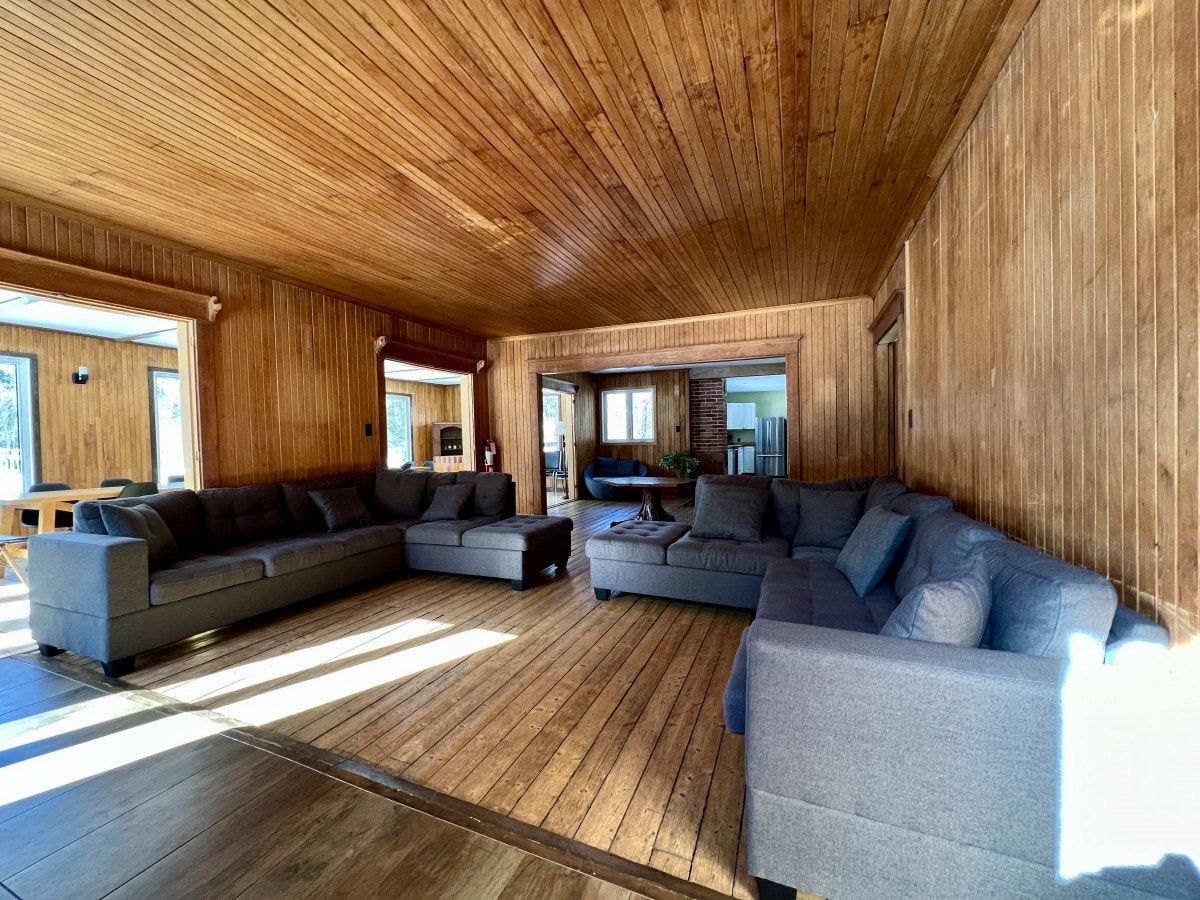 Ein großzügiger Wohnbereich mit einem großen Ecksofa, einem Couchtisch und einer Holzbalkendecke.