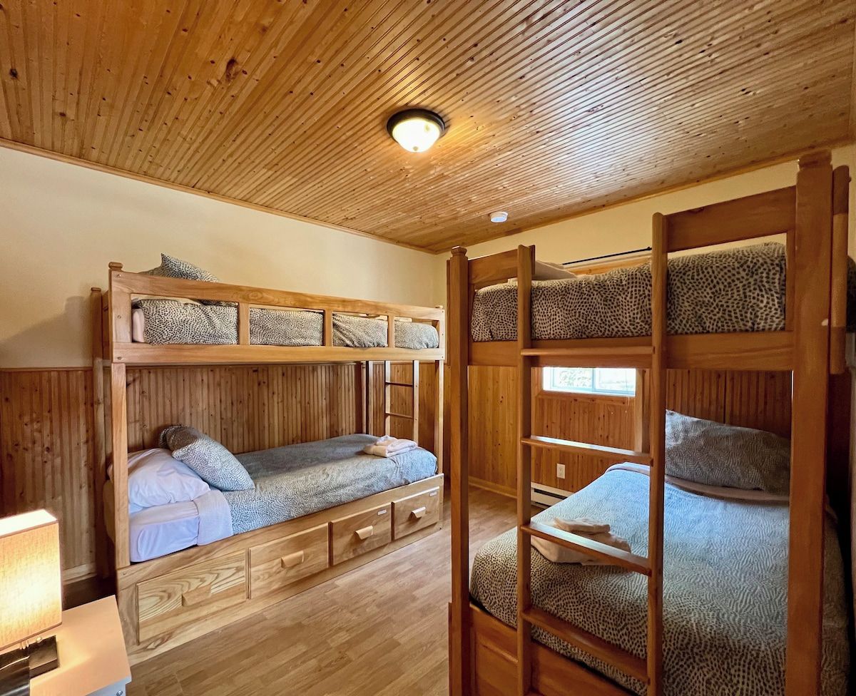 Dormitorio con literas, paredes de madera y techo inclinado.