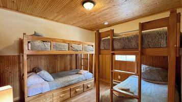 Dormitorio con literas, paredes de madera y techo inclinado.