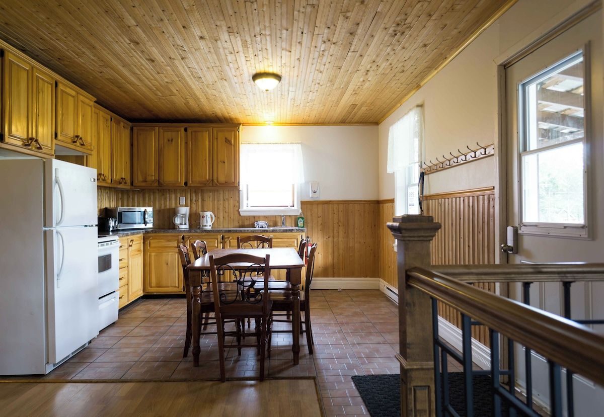 A kitchen with wooden cabinets, a dining table, and chairs.