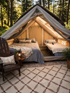 A tent with a bed and seating area, surrounded by a forest. - Weekend Getaway Relax & Recharge 5 acres Nature Retreat & Dog Heaven!  (Mokelumne Hill)