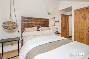A bedroom with a wooden headboard, a hanging light fixture, and a wooden wardrobe.