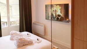 Ein Schlafzimmer mit Bett, Spiegel, Gemälde und Fenster.