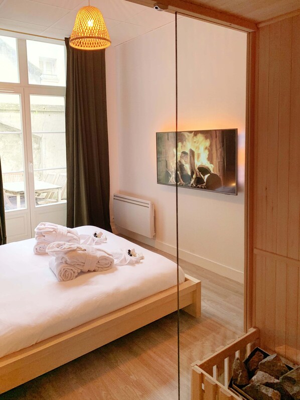 A bedroom with a bed, a mirror, a painting, and a window.