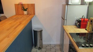 Eine kleine Küche mit Holztischplatte, Mülleimer, Mikrowelle und Kaffeemaschine.