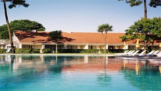 A swimming pool with a building in the background. - Clube Pinhal Da Foz (Esposende)