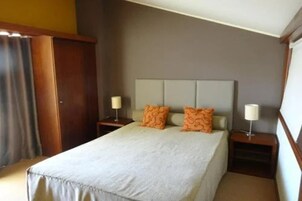 A hotel room with a bed, two nightstands, and a wooden wardrobe.