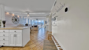 A modern kitchen with a large island, white cabinetry, and a view to the outside. - Dolphin Point 502B | Harbor front Views + Pool | Near Beach | Amenity Perks (Destin)