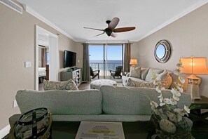 Une chambre d’hôtel avec un balcon, un ventilateur de plafond, une télévision, un canapé et une lampe.