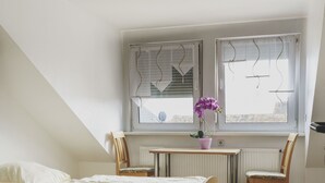 Un dormitorio con dos camas, un escritorio, una silla y una ventana con persianas.