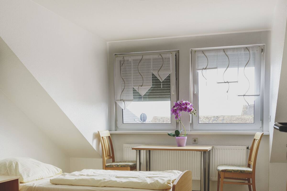 Un dormitorio con dos camas, un escritorio, una silla y una ventana con persianas.