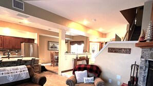 A cozy living room with a fireplace, a dining area, and a kitchen. - Charming Rustic Townhome in the Heart of the Villages at Seven Springs (Champion)