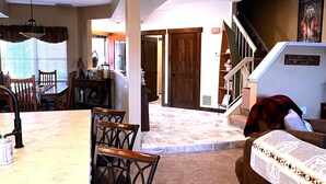 A spacious living area with a dining table, chairs, a sofa, and a staircase leading to another level. - Charming Rustic Townhome in the Heart of the Villages at Seven Springs (Champion)