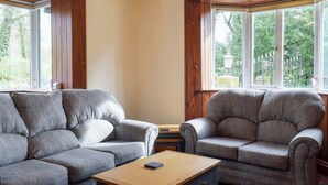 Une pièce avec deux fauteuils gris et une table basse en bois.
