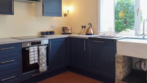 Une cuisine moderne avec des meubles de couleur bleu foncé, un four encastré, une bouilloire et un grille-pain.