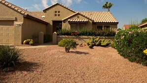 A house with a tiled roof, a garage, and a gravel driveway. - It’s AZ Time...Relax in a private heated pool, Golf, Spring Training, Hiking! (Surprise)