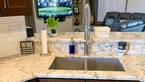 A kitchen with a granite countertop, stainless steel sink, and dark wooden cabinets. - It’s AZ Time...Relax in a private heated pool, Golf, Spring Training, Hiking! (Surprise)