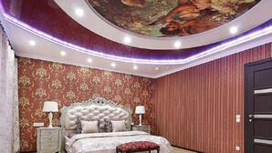 Un dormitorio con una cama grande, dos mesitas de noche, un banco y una puerta.