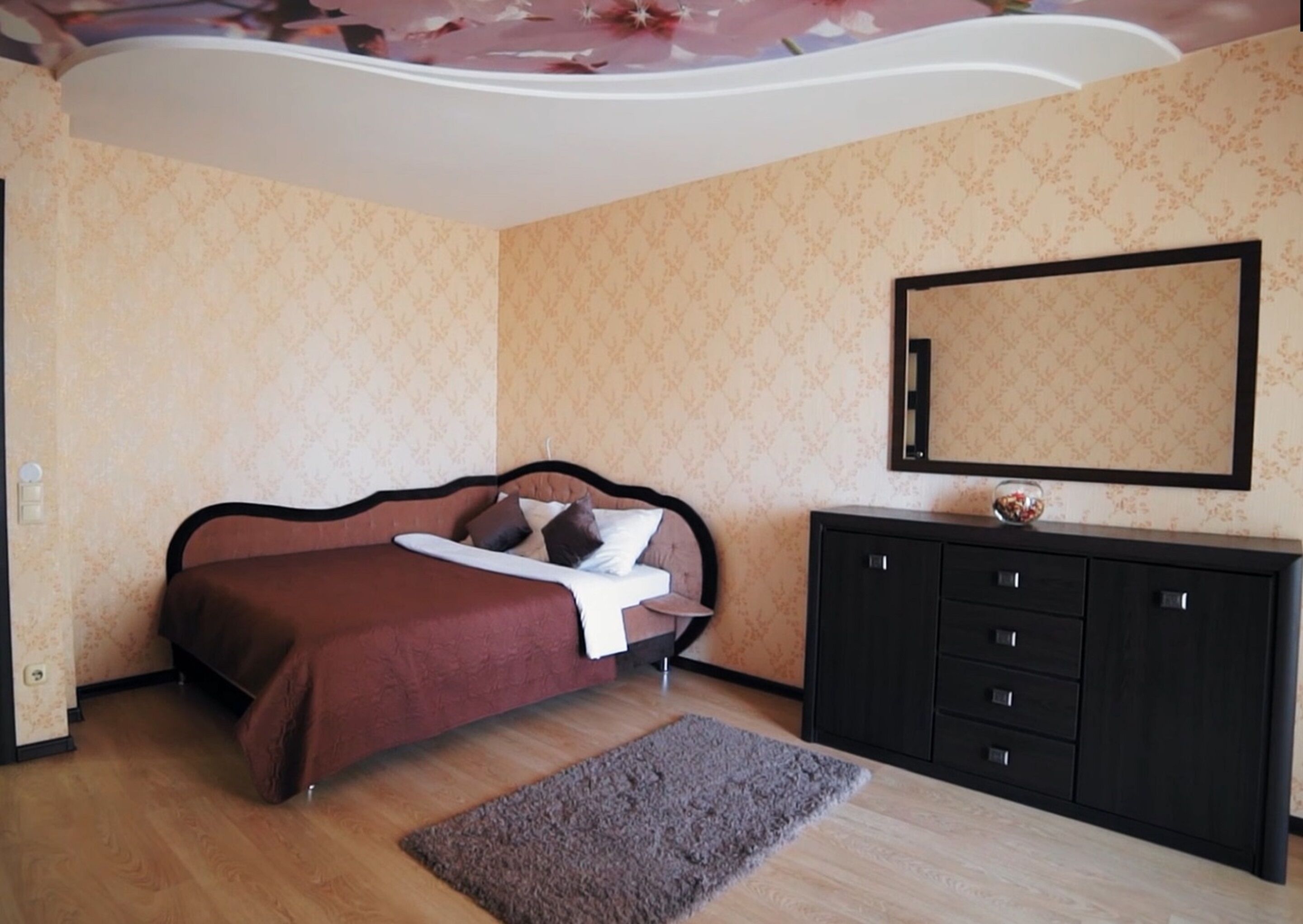 Una camera da letto con un letto, una cassettiera, uno specchio e un tappeto.