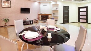 Un comedor moderno con una mesa redonda dispuesta para cuatro personas, una chimenea y un televisor montado en la pared.