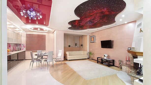 Una sala de estar moderna con un diseño curvo, un televisor de pantalla plana montado en la pared, un sofá y un comedor con mesa y sillas.