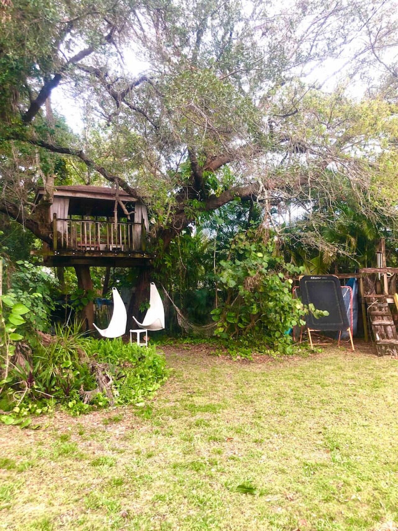 Uma casa na árvore com um deck de madeira e uma rede.