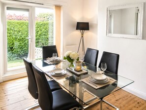 A dining area with a glass table, black chairs, and a vase with white flowers. - HC Property - Mountford (Durham)