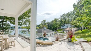 Une terrasse couverte avec une piscine, du mobilier d’extérieur et une vue sur un lac et des maisons.
