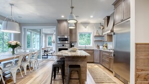Une cuisine moderne avec des meubles en bois, des appareils en acier inoxydable et un îlot central doté de tabourets.