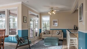 A spacious living area with a sofa, ottoman, and chairs, a kitchen counter, and a ceiling fan. - Large 5 bedroom, standalone home with private hot tub, BBQ and pet friendly too! (Silver Star Mountain)